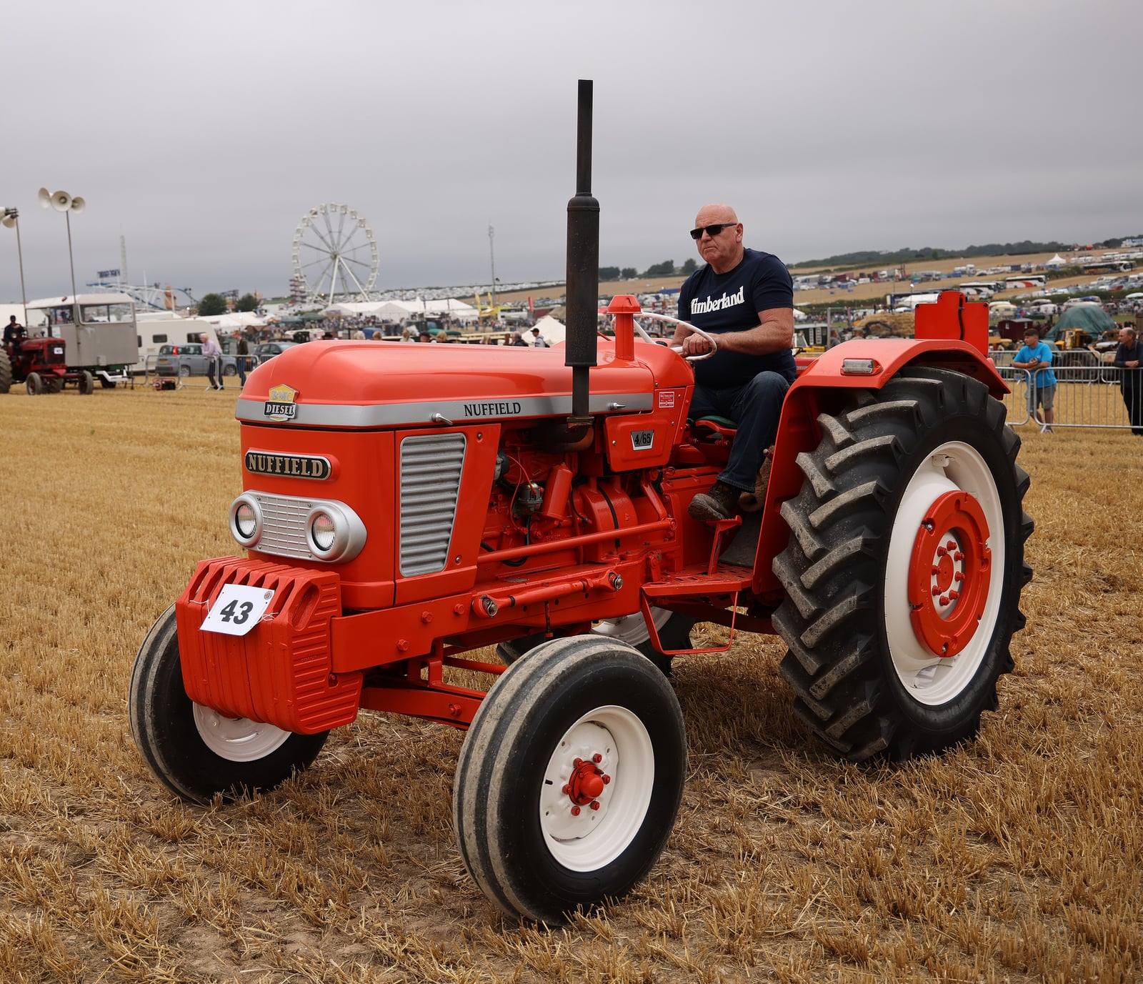 An orange Nuffield 465 tractor at the Great Dorset Steam Fair, a rider aboard