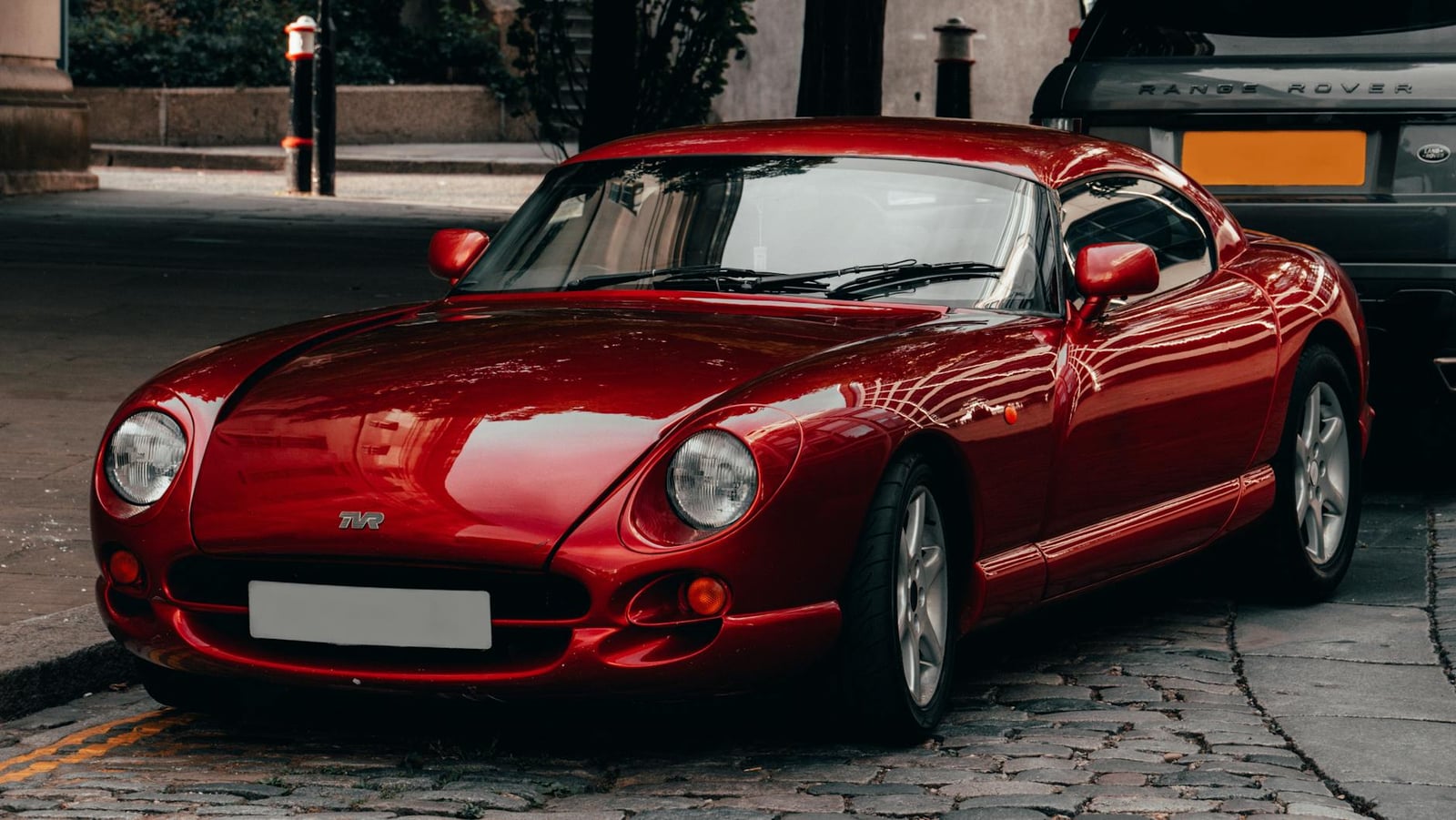 A red TVR Cerbera coupe parked on a cobbled street, front three-quarter view