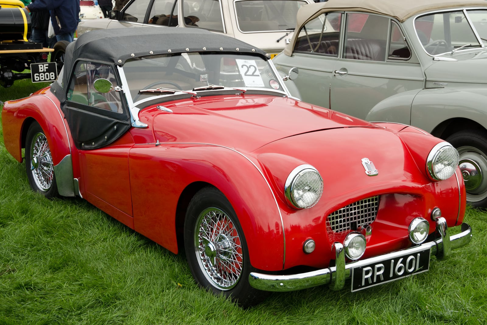 A red Triumph TR2 with the hood up, UK registration RR 1601, front three-quarter view on a show field