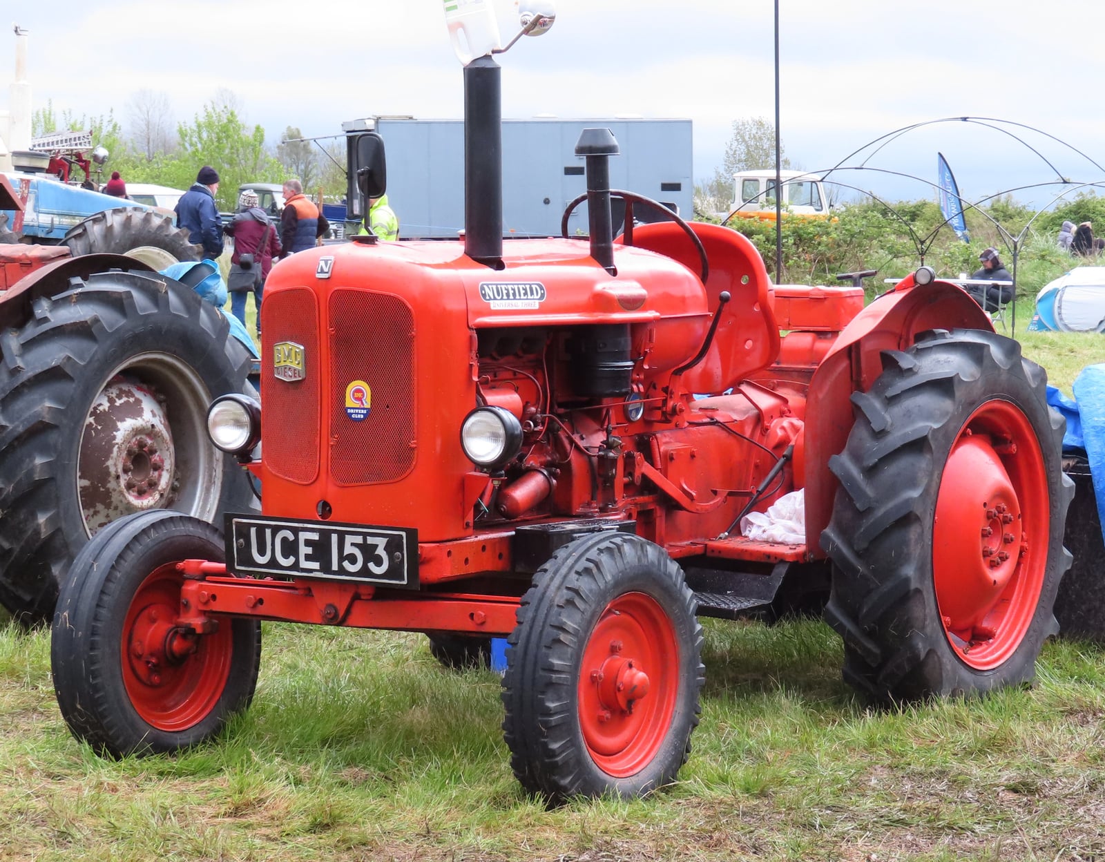 A vivid orange Nuffield Universal Three, registration UCE 153, at a show