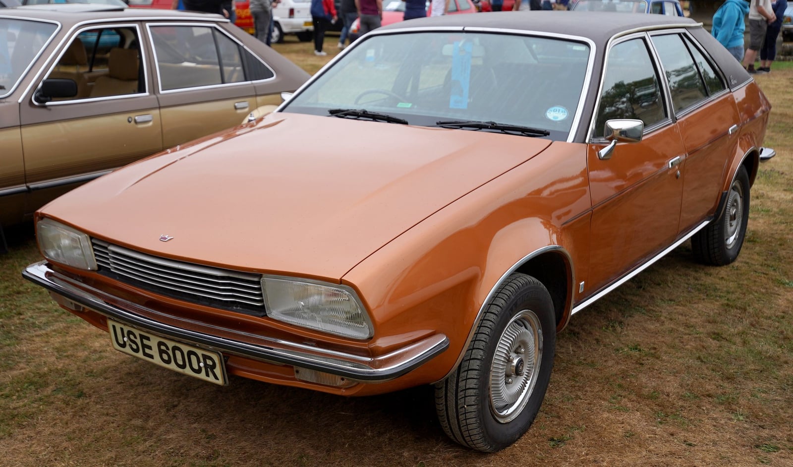 A bright orange Austin Princess wedge saloon (R plate, 1976-77) with black vinyl roof, front three-quarter view at an outdoor classic car show