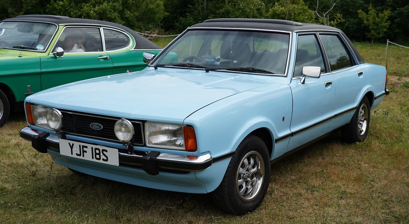 A light blue Ford Cortina Mk5 Ghia four-door saloon at a show, front three-quarter view